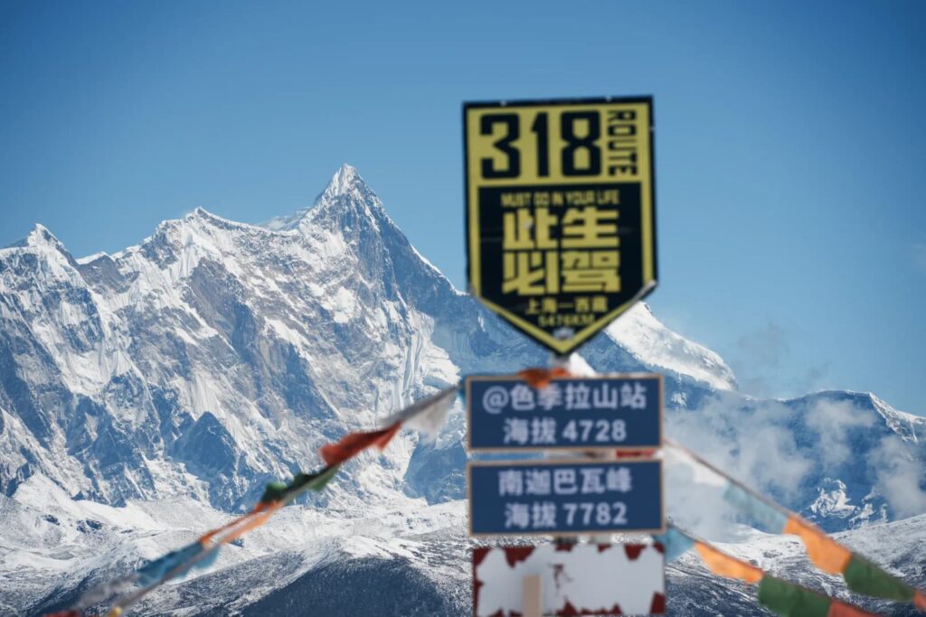 色季拉山口海拔4728米標示牌,遠眺南迦巴瓦峰雪山,經幡飄揚
