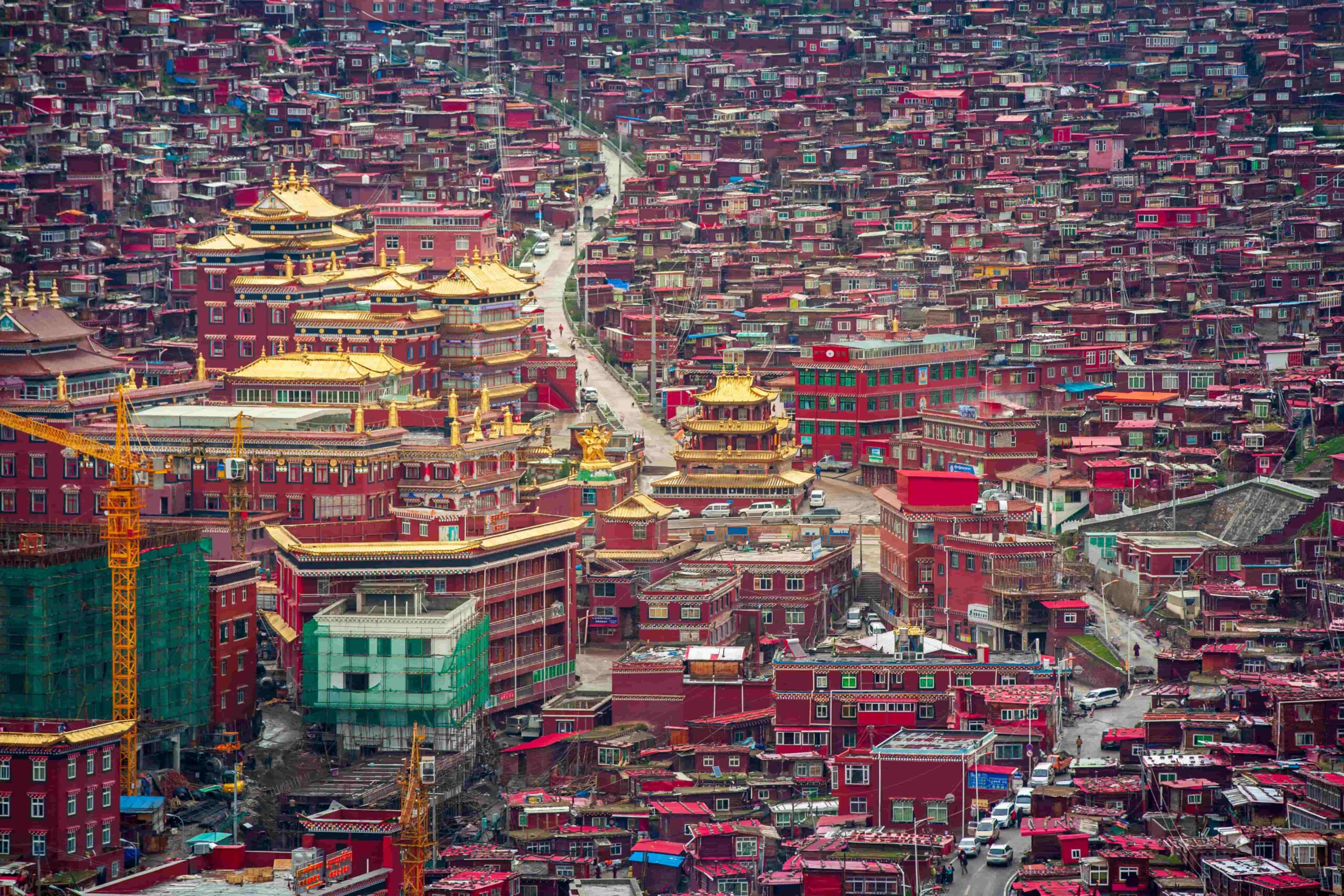色達喇榮五明佛學院航拍全景,金頂殿宇與絳紅色木屋密佈山谷,四川甘孜藏區