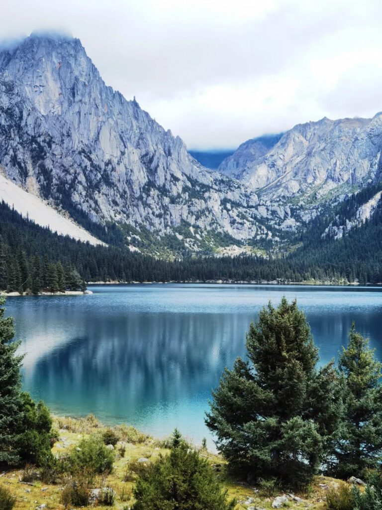 巴塘措普溝神湖深藍湖面與峽谷岩壁,原始針葉林環抱,四川甘孜川西藏區