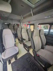旅遊團專用15座中巴車內部,灰色皮椅配安全帶,2025年新車,車廂寬敞舒適