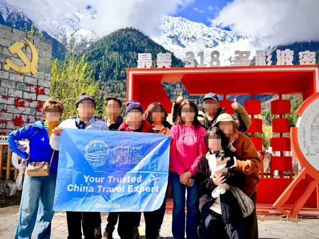 China2Go 評價如何?國旅環球西藏團客人怎麼說 - CITS China International Travel Service 國旅環球西藏團客人在波密「最美318」地標前,手持 CITS 中國國旅旗幟合影
